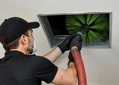 Air duct cleaning technician removing dust